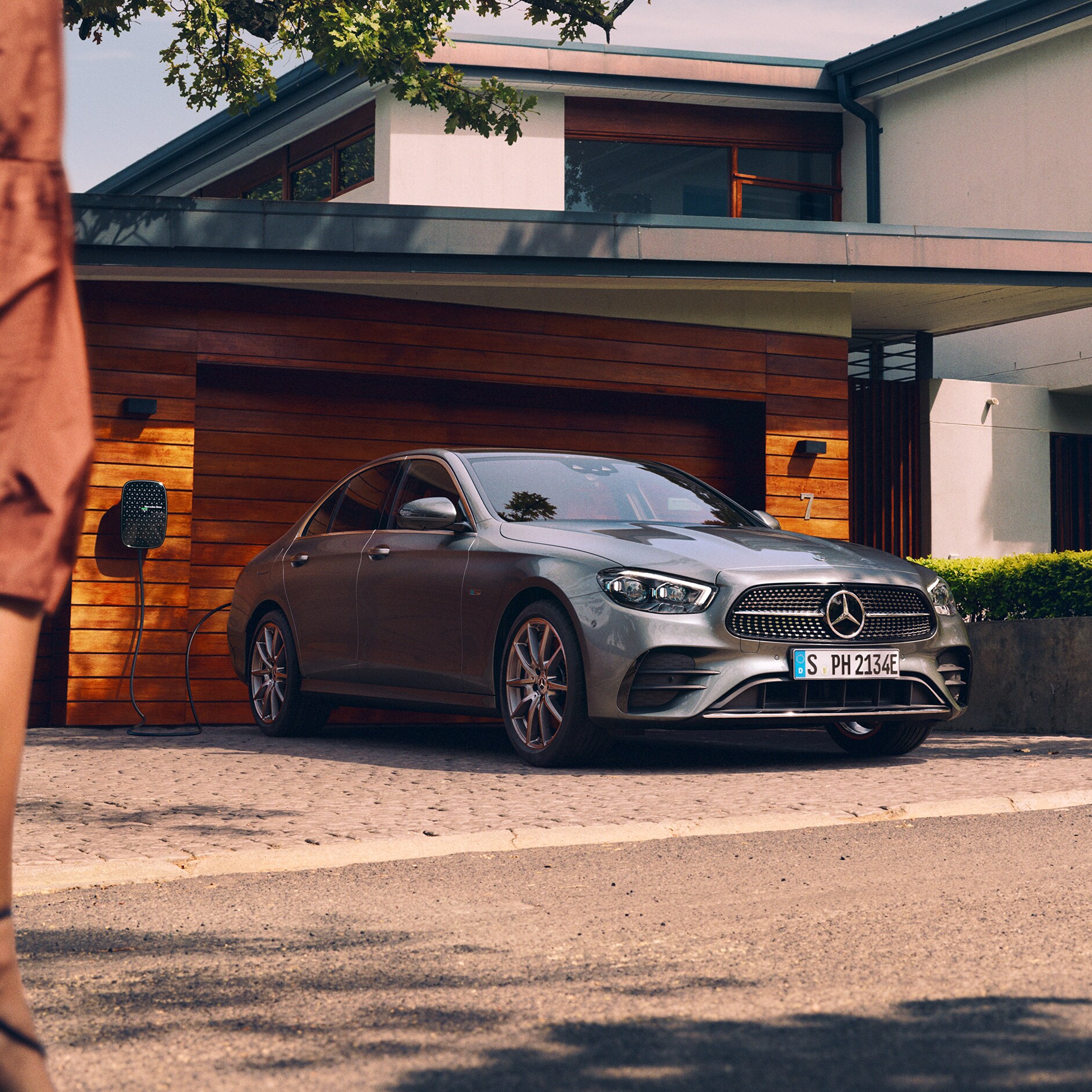 Electric mobility | E-Class Saloon | Mercedes-Benz The image shows the Mercedes-Benz E-Class Saloon being charged outside a garage.